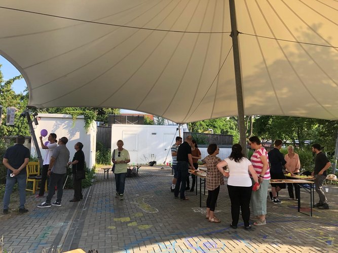 Menschen stehen unter einer Überdachung bei einer Beteiligung