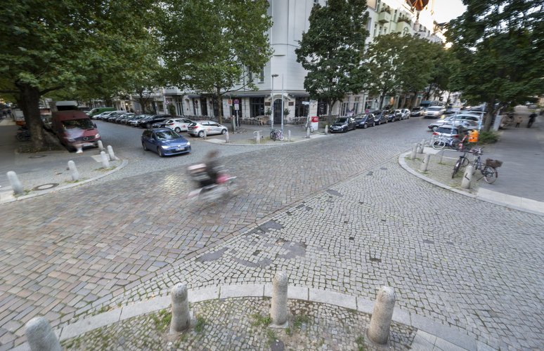 Blick von oben auf eine gepflasterte Straßenkreuzung in Prenzlauer Berg mit Auto
