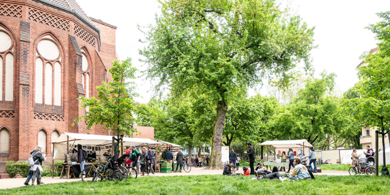 grüne Wiese vor einer Kirche aus roten Backsteinen. Auf der Wiese stehen Marktst