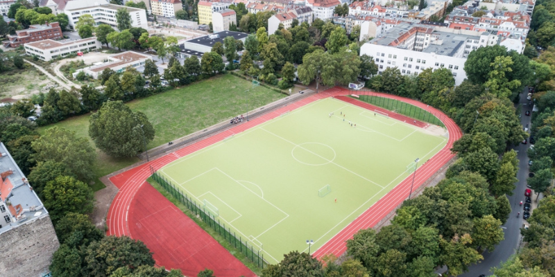 Luftbild von dem Sportplatz mit grünen Sportfeld und roter Bahn rundum