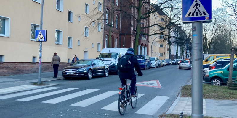 Fahrradfahrer fährt auf Straße über einen Zebrastreifen