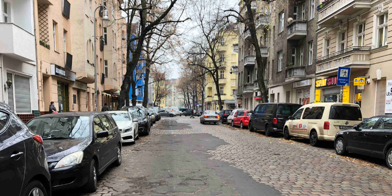 Straße in baufälligen Zustand mit parkenden Autos auf beiden Seiten