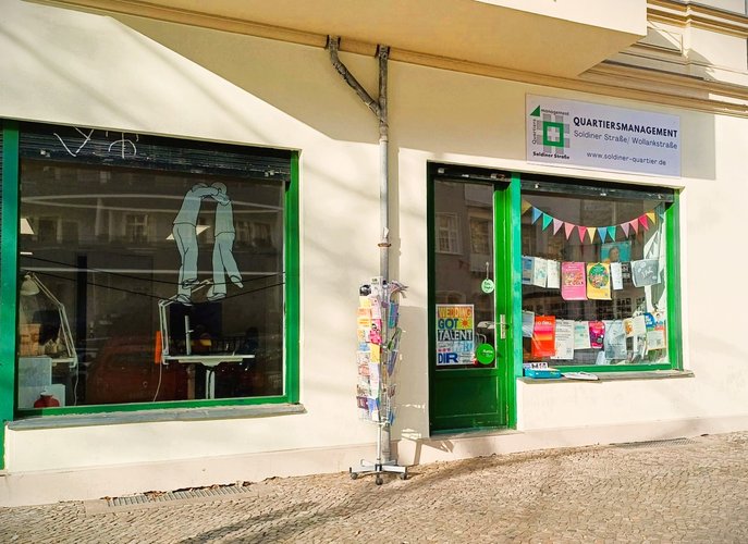 Die Außenfassade des QM Soldiner, zwei Ladenfenster mit Eingangstür