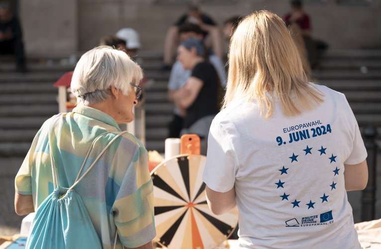 Bild von zwei Menschen von hinten. Die eine Person trägt eine Europa-Tshirt.