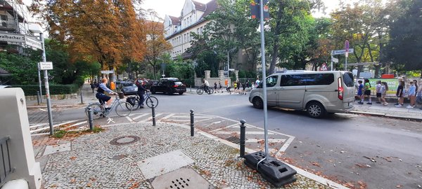 Eine Kreuzung im Schulbereich mit Autos, Fahrradfahrenden und Schüler_innen