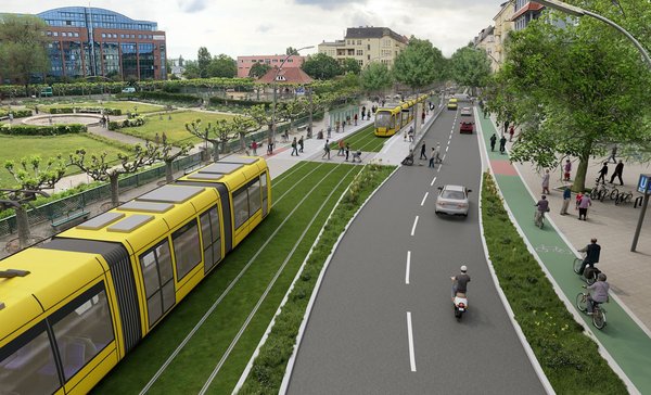 Straßenbahn fährt auf einem Rasengleis neben einer Straße