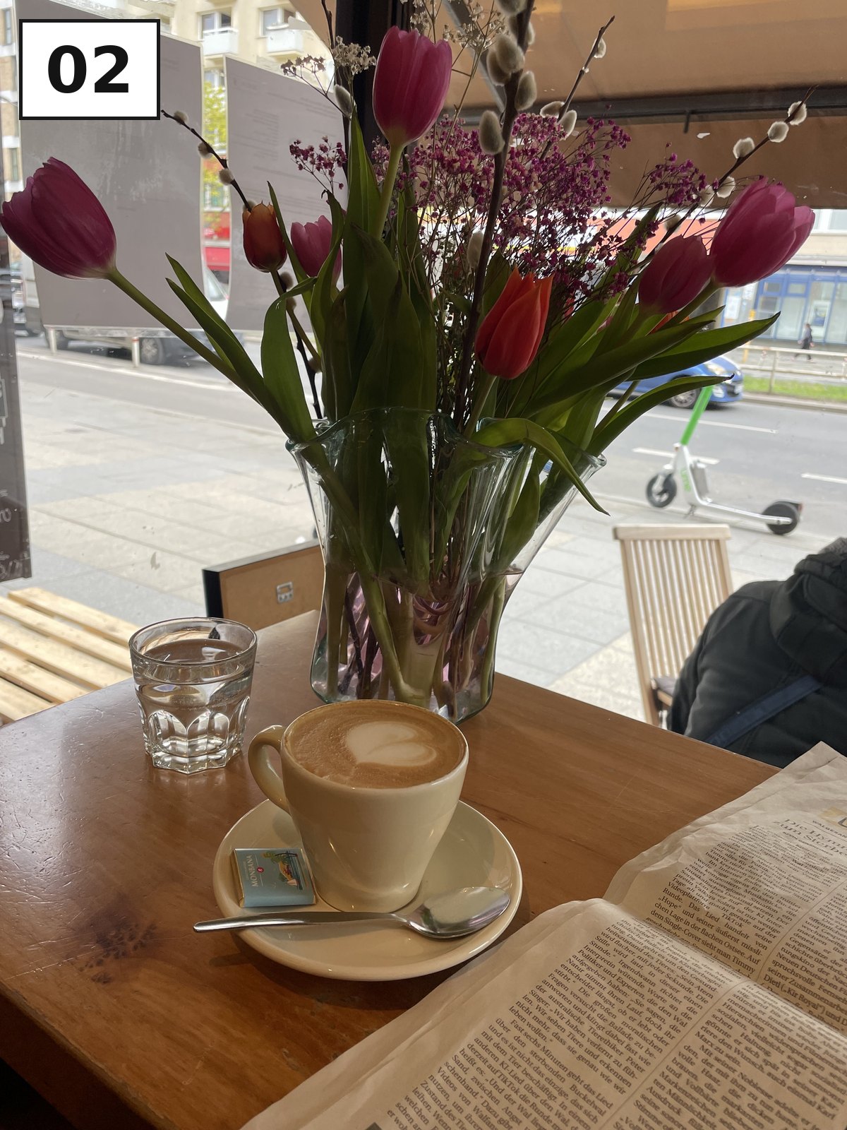 Tulpenstrauß und Cappuccino auf einem Cafétisch am Fenster