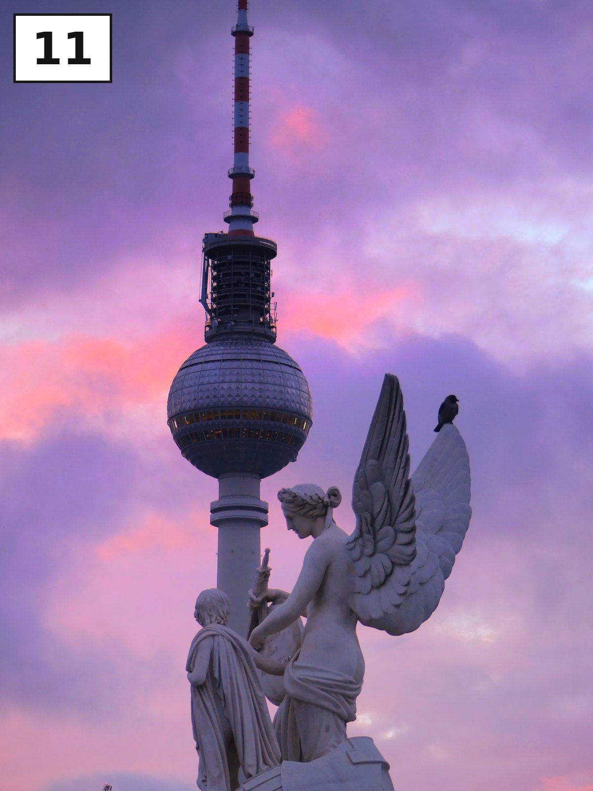 Weiße Engelsskulptur vor dem Fernsehturm, der Himmel leuchtet rosa und violett