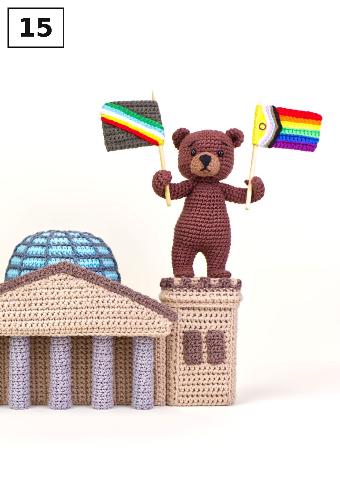 Gehäkelter Teddybär mit Regenbogenfahnen auf gehäkeltem Reichstag und Dom
