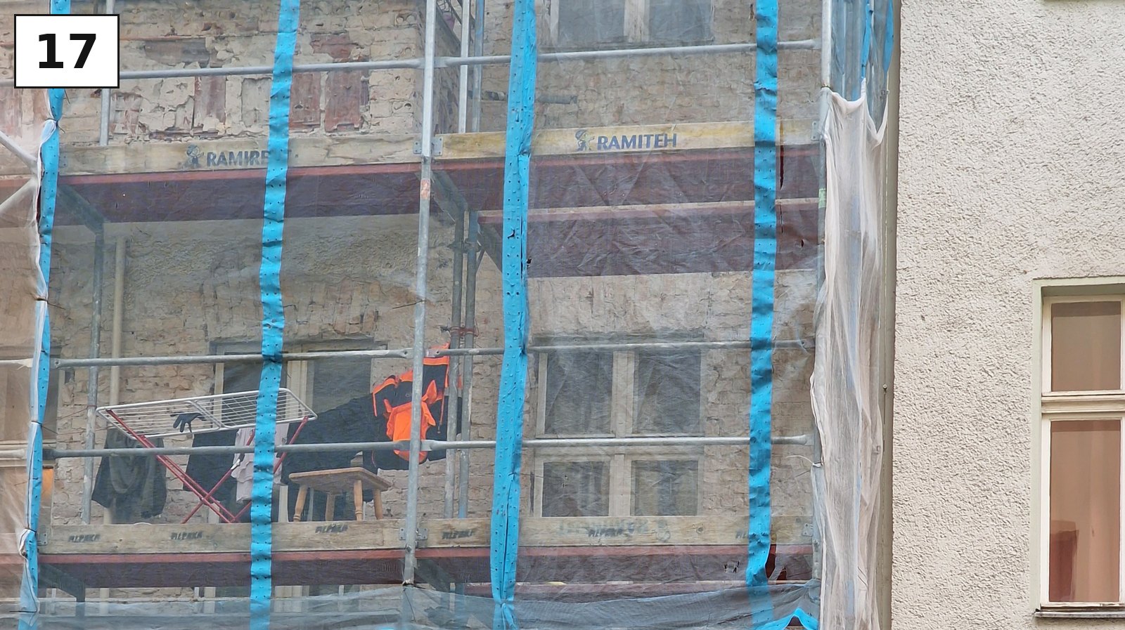 Hausfassade hinter einem Baugerüst mit blauer Folie