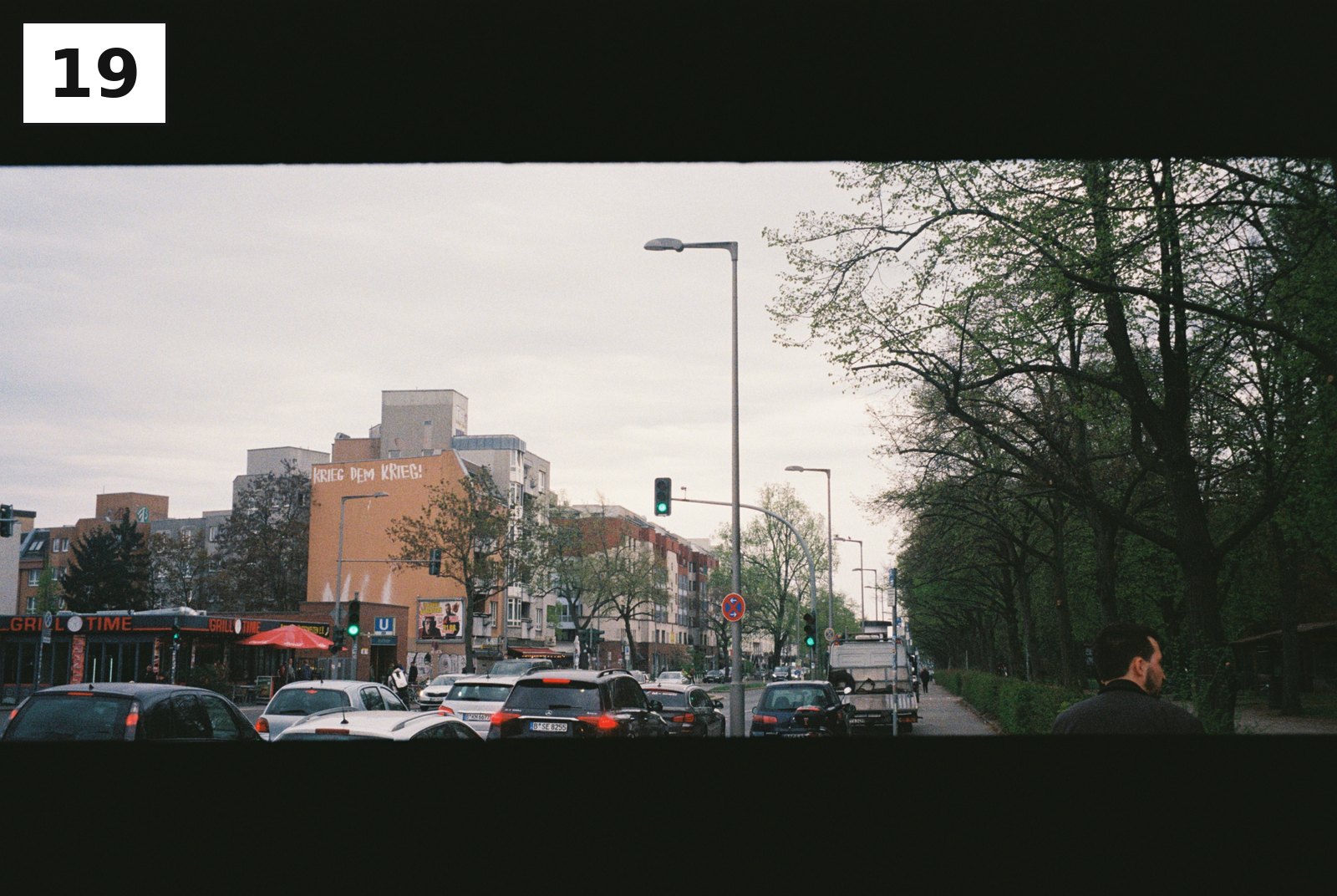 Straßenkreuzung mit Autos und Bäumen, dahinter ein Bürogebäude